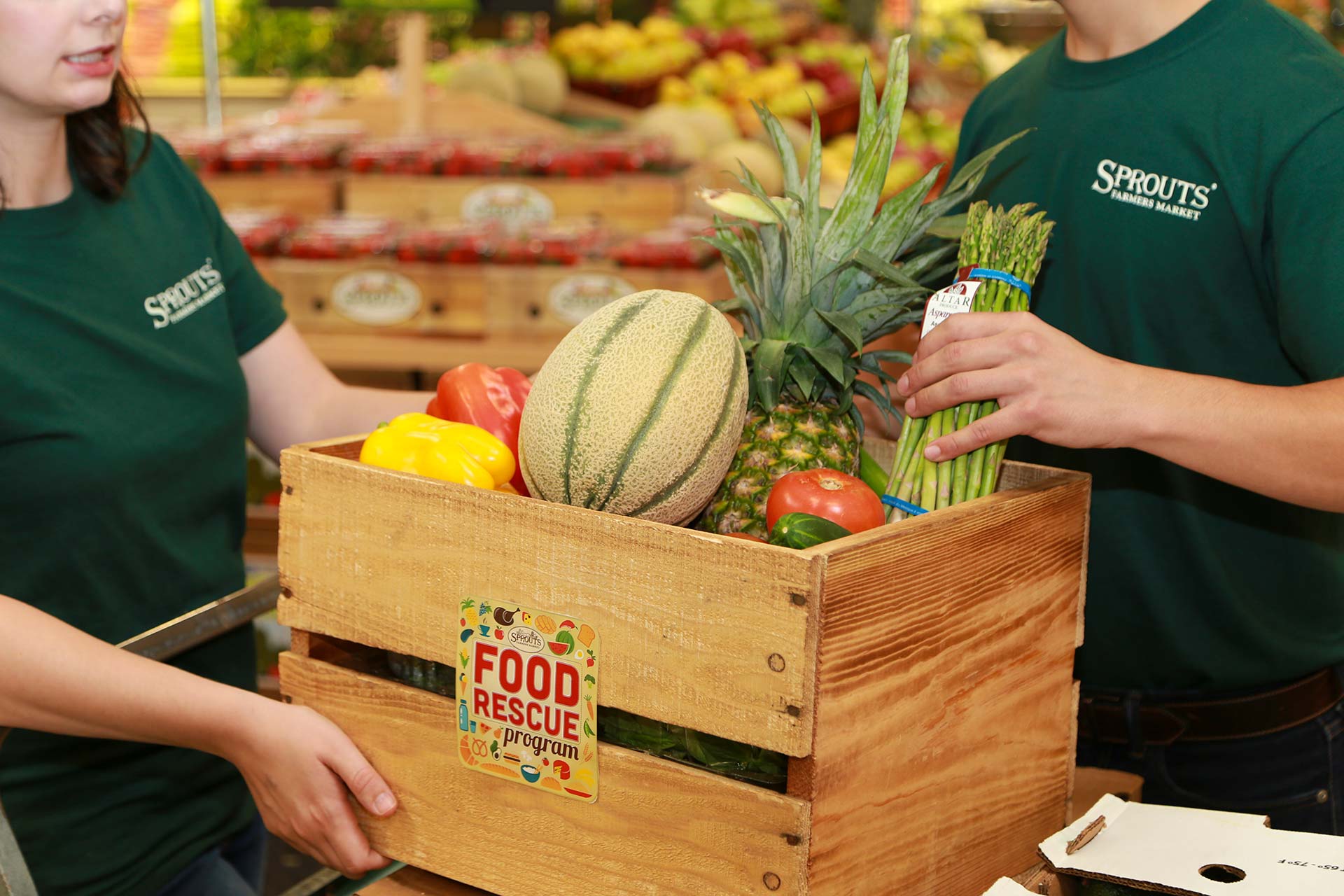 Sprouts store employees fill a crate with produce
