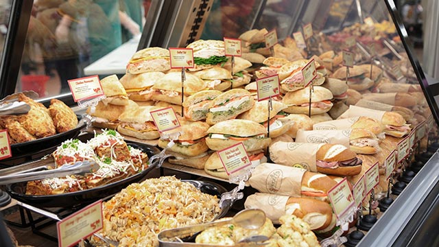 A glass case full of delicious deli sandwiches