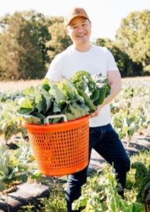 Danny Seo with basket of lettuce in a garden