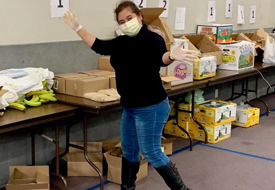 Woman at a food bank eagerly packing donation boxes.