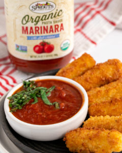 cheese sticks on a plate with a bowl of marinara