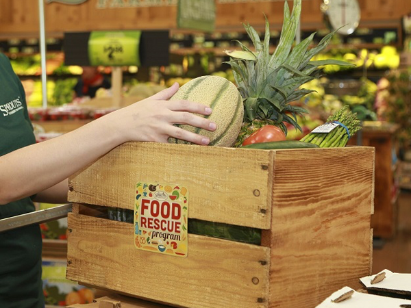 Sprouts team member loading produce into a crate
