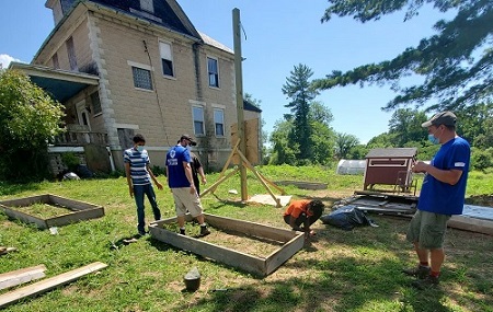 Volunteers build gardens behind a house.