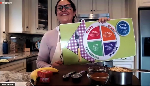 A woman holds up a nutrition poster showing how to construct a healthy, balanced meal.