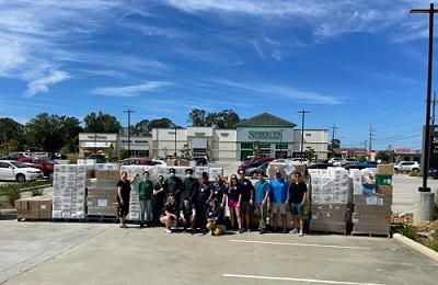 Sprouts team members stand with 15 pallets of donated food in the background