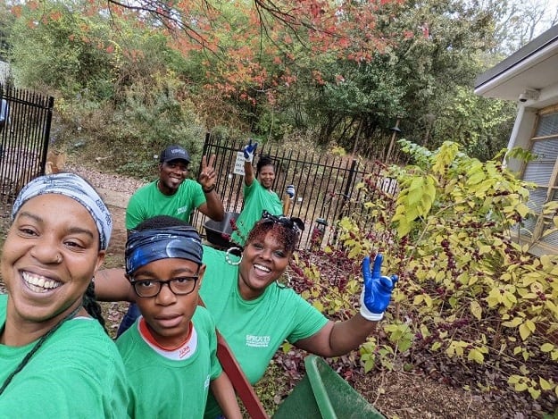 Volunteers smile while helping out in a school garden.