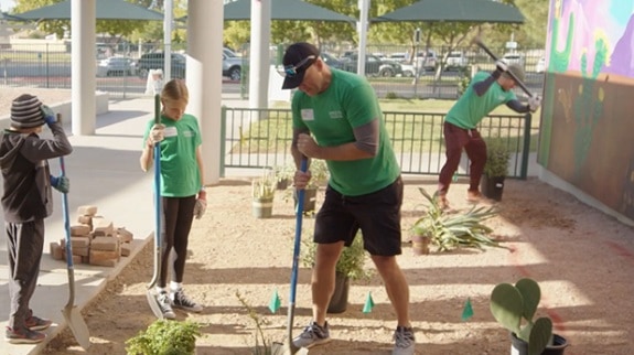 Adults and children use tools to build out a school garden.