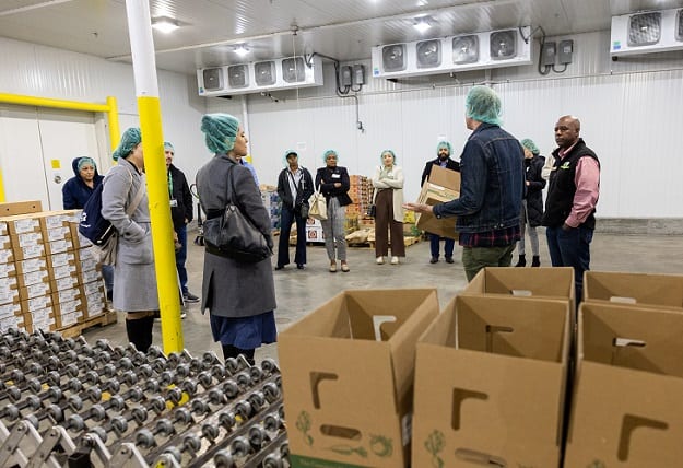 A group huddles inside of a produce distribution center for a tour.