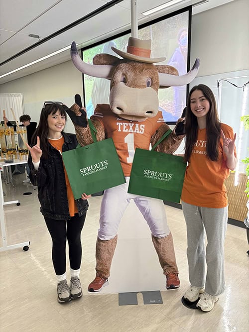 Women with mascot holding Sprouts canvas bags